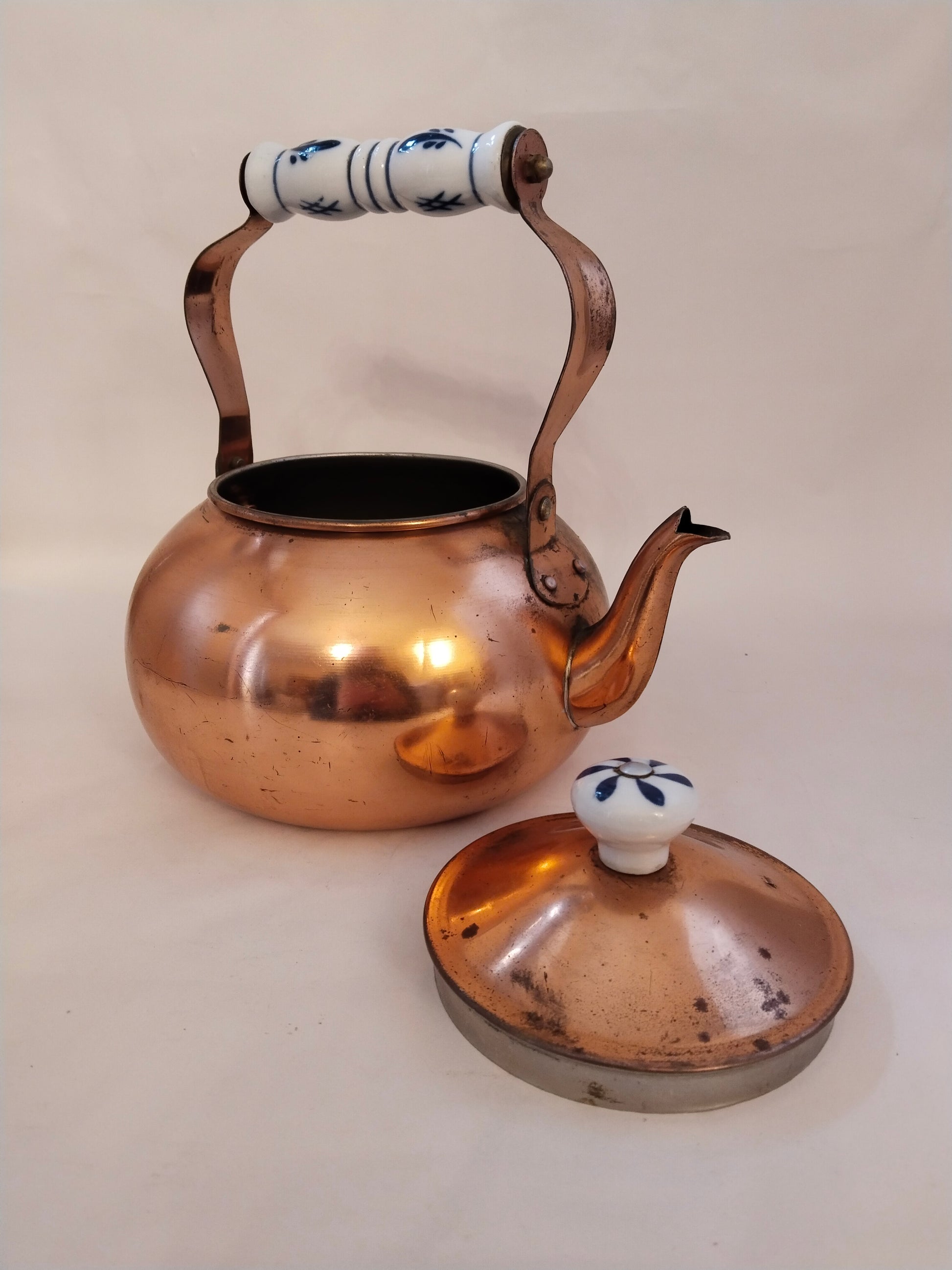 Vintage Kupfer-Teekanne mit bauchiger Form und glänzender Oberfläche mit geöffnetem Deckel.