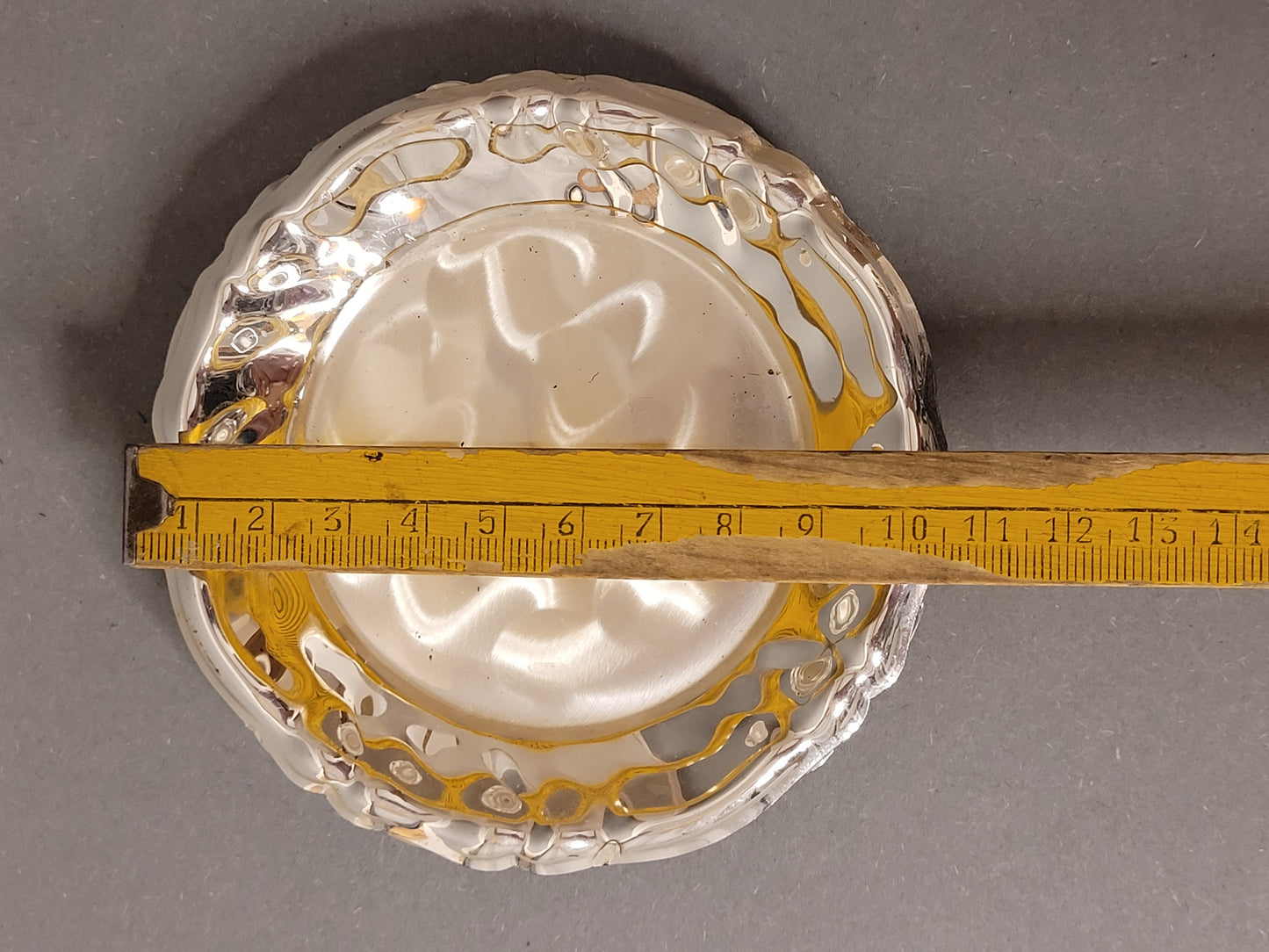 Draufsicht auf einen versilberten Untersetzer mit Maßband (ca. 10 cm)