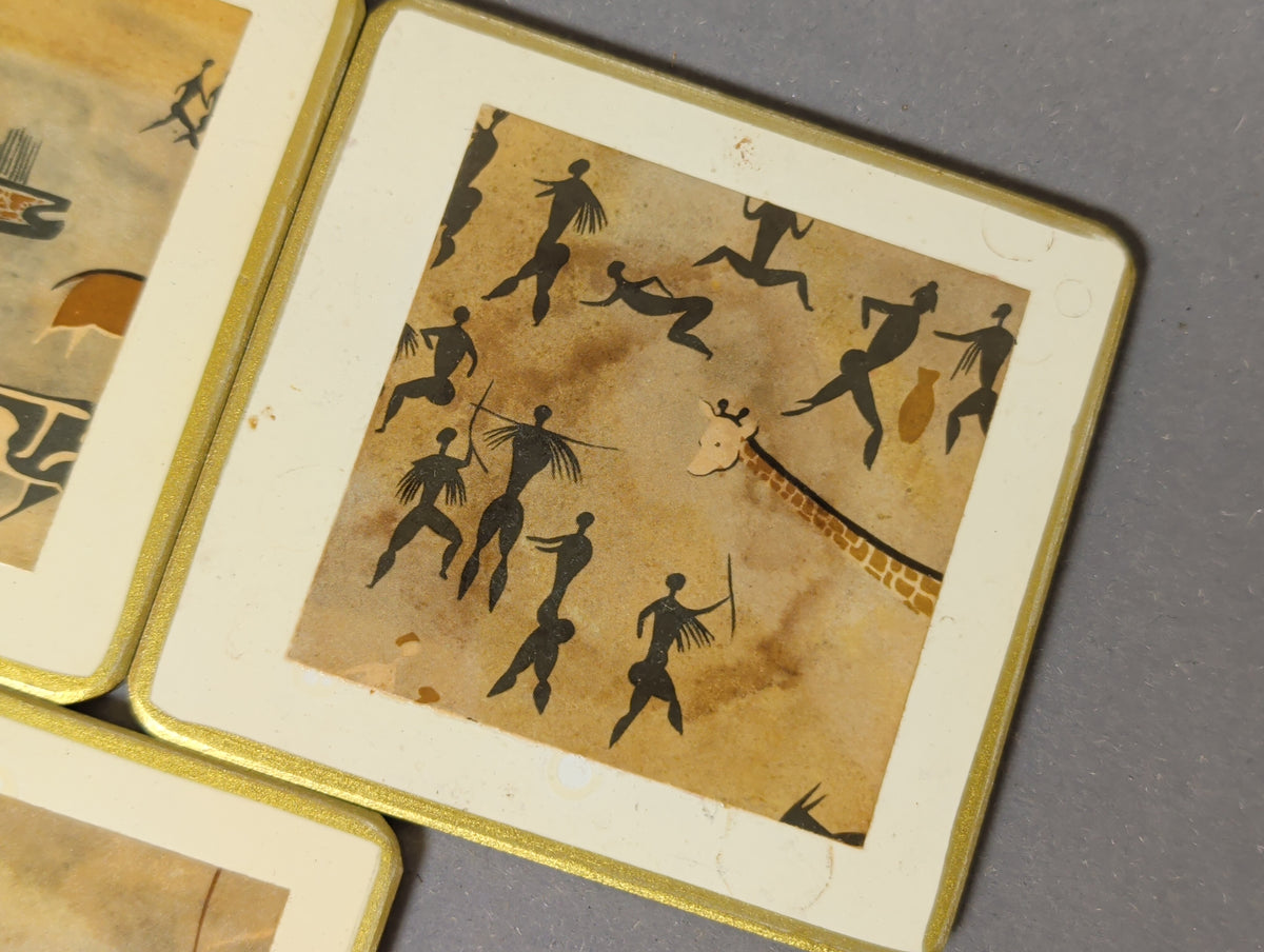Detail Untersetzer mit schwarzen tanzenden Figuren, Krug und Giraffe, auf dem cremeweißen Rand schwache runde Abdrücke