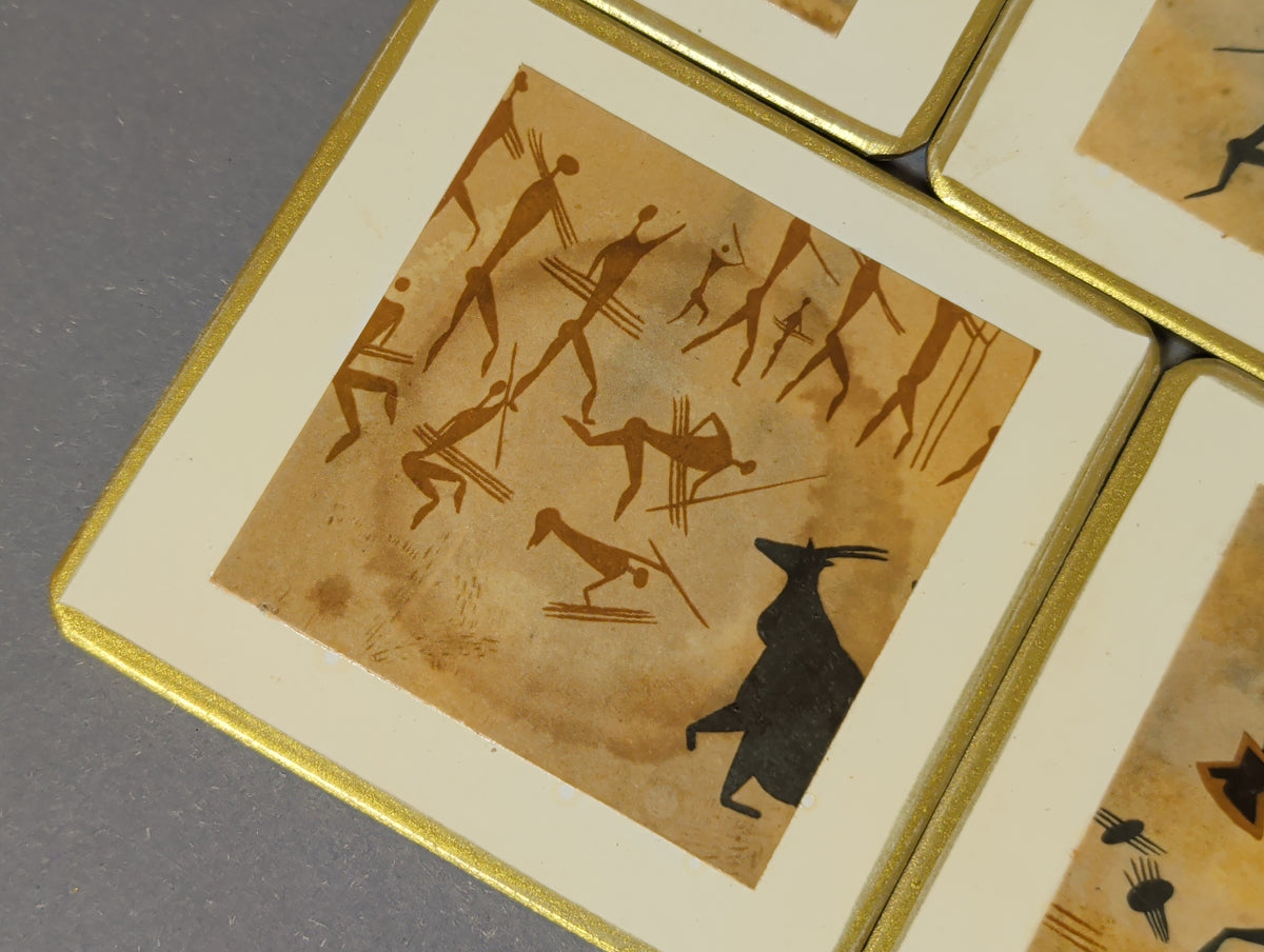 Detail Untersetzer mit braunen Figuren mit Speeren und schwarzem gehörntem Tier, runder Glasabdruck im Bild