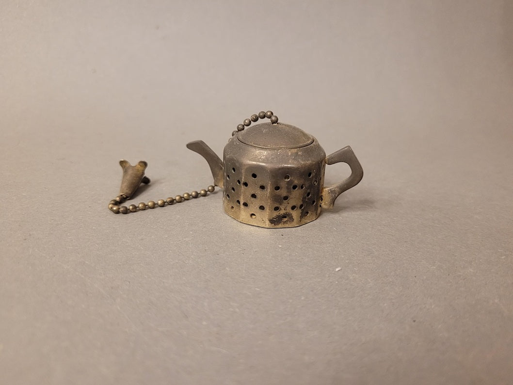 Seitenansicht des Teesiebs mit ausgebreiteter Kugelkette zur Sicherung des Deckels.