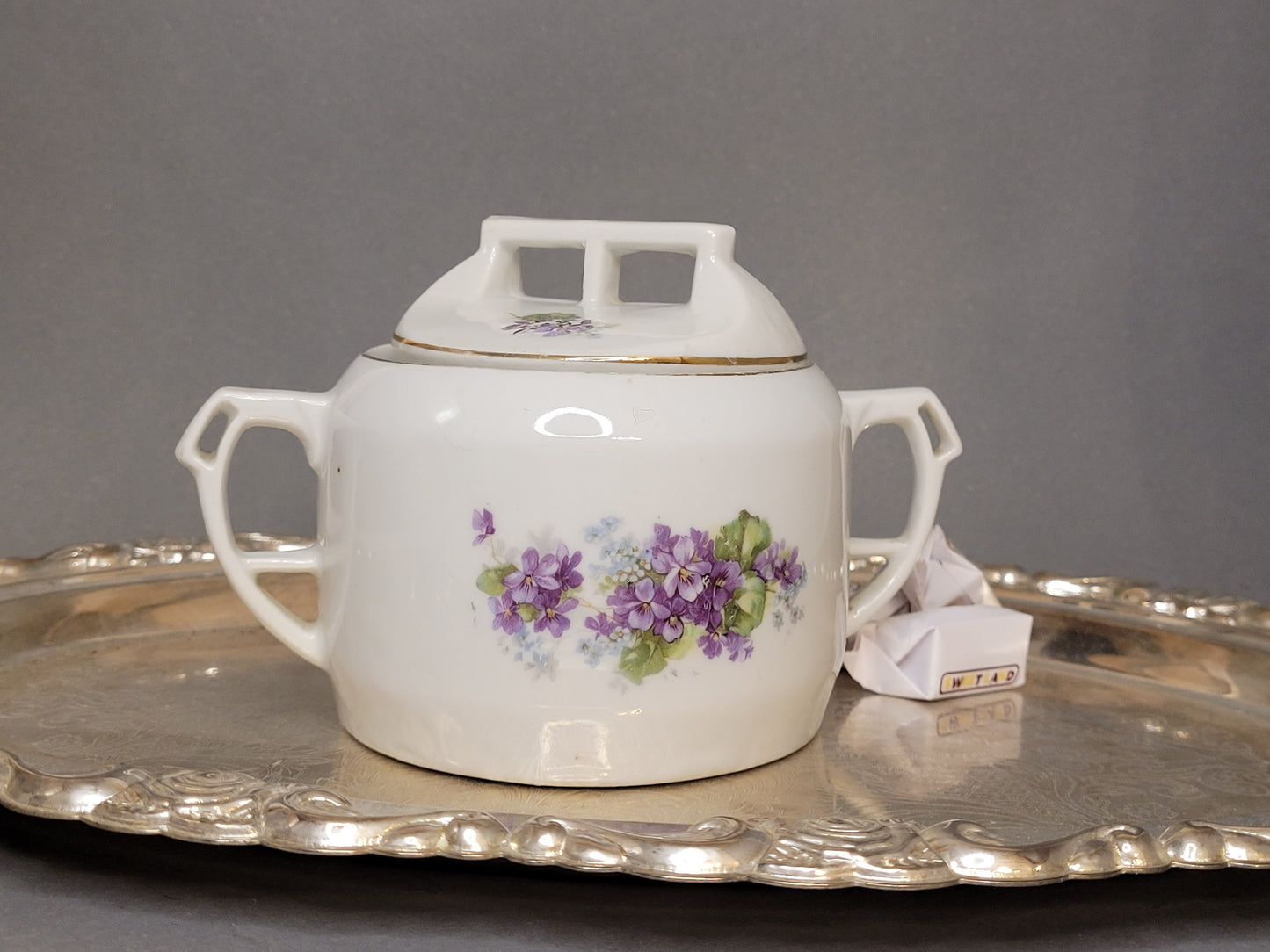 Porzellan-Zuckerdose mit violetten Blumen und zwei Henkeln auf Silbertablett