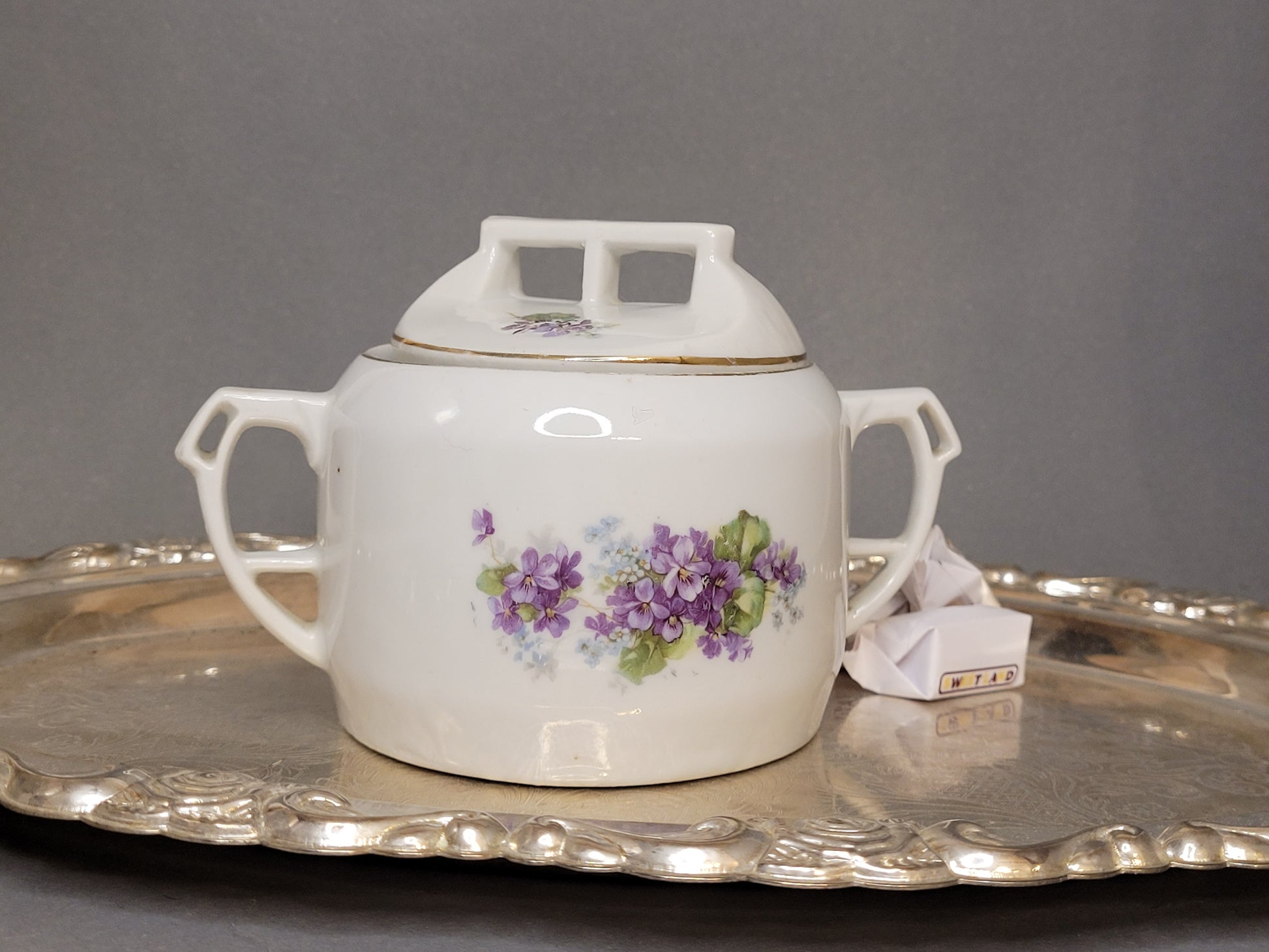 Porzellan-Zuckerdose mit violetten Blumen und zwei Henkeln auf Silbertablett