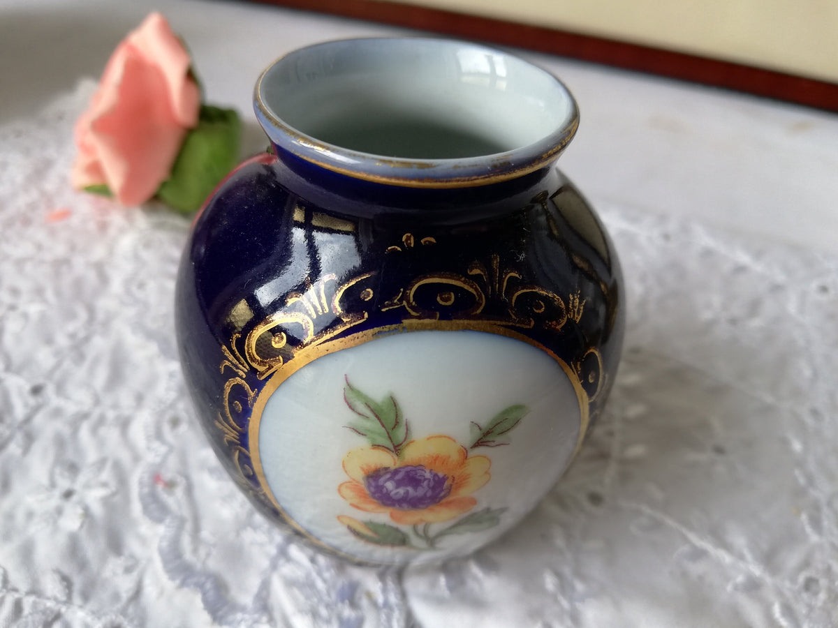 Blumenmotiv auf weißem Grund im goldgerahmten Medaillon
