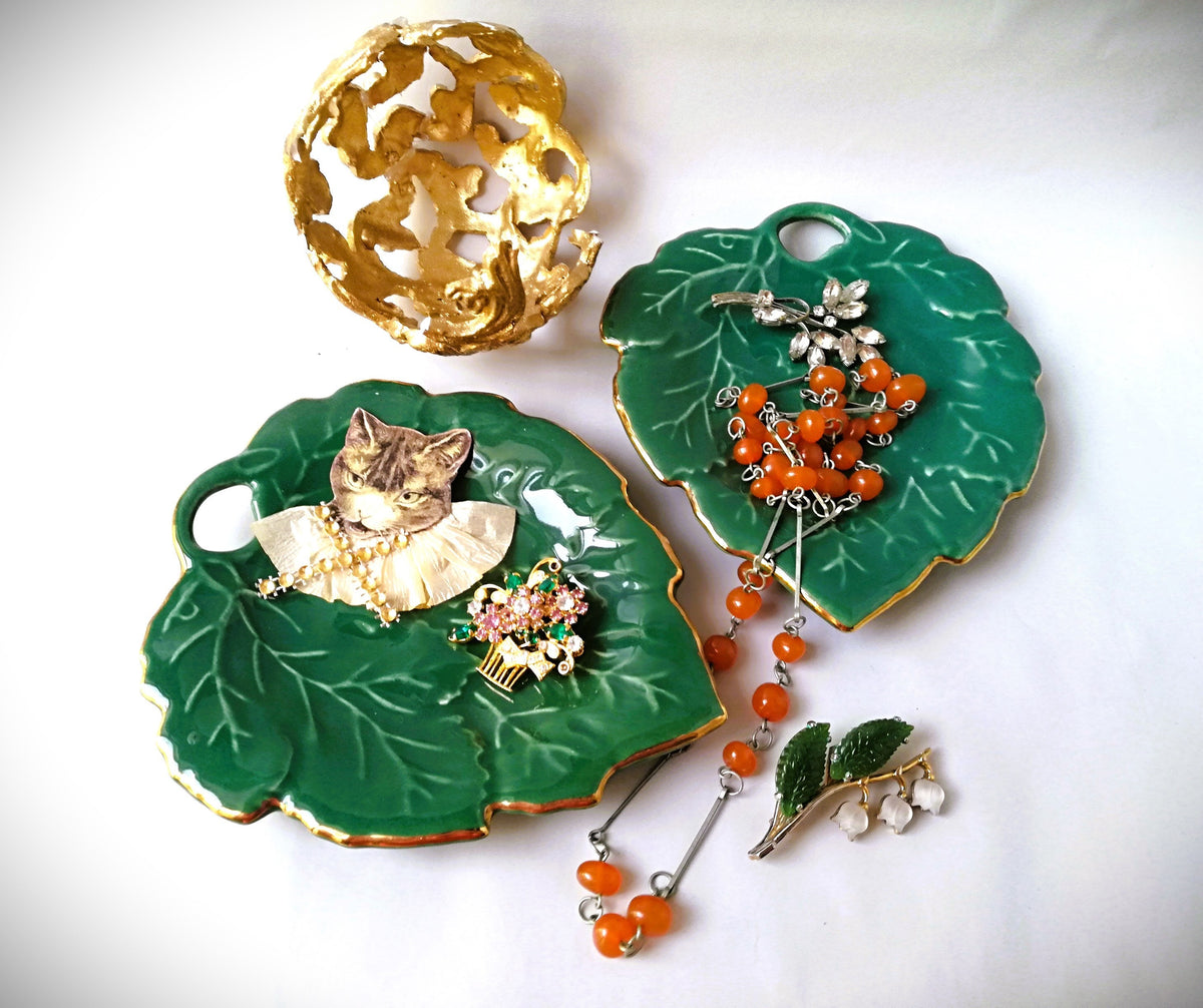 Stylish vintage coaster in the shape of a green vine leaf with gold trim