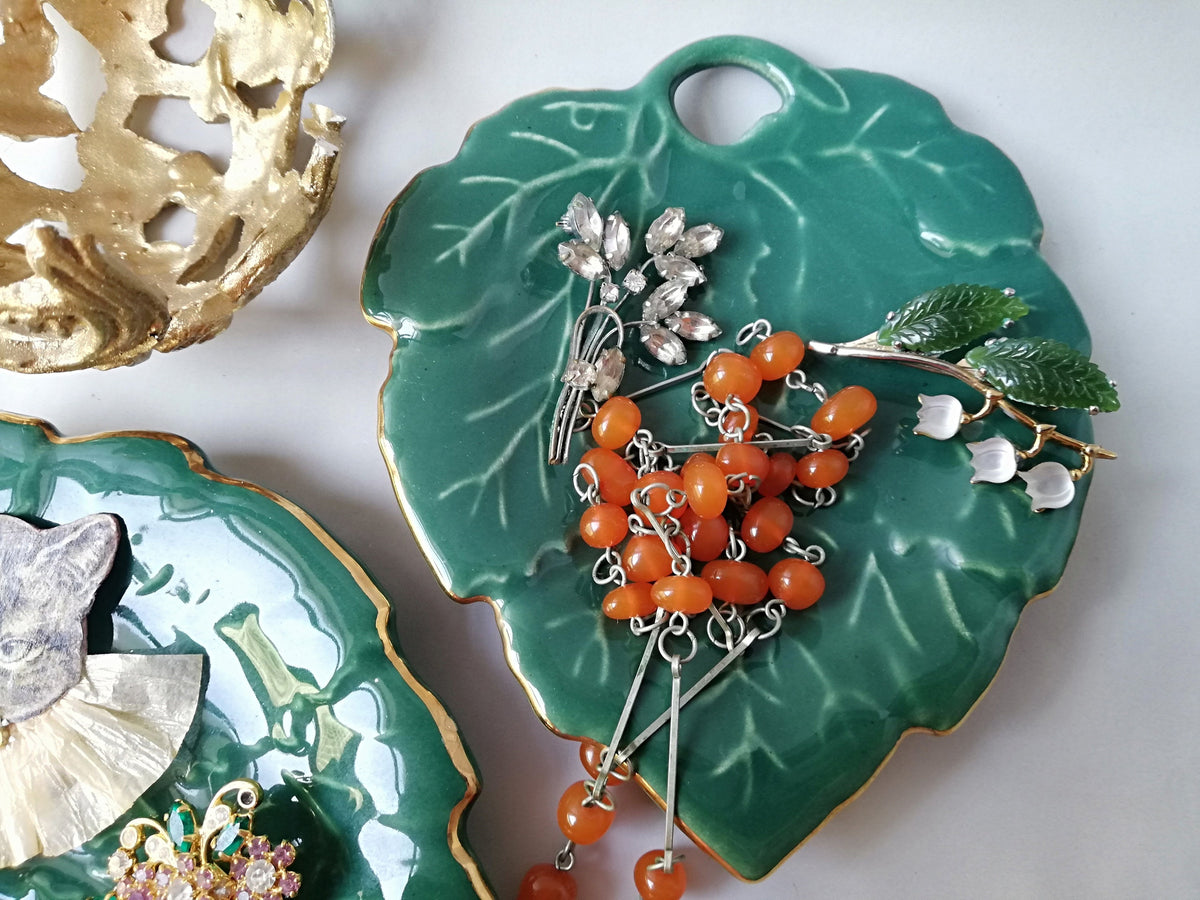 Stylish vintage coaster in the shape of a green vine leaf with gold trim