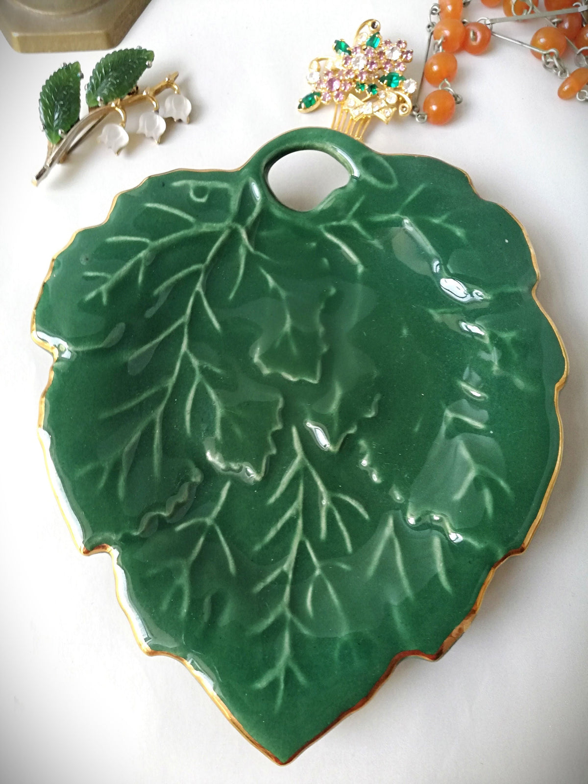 Stylish vintage coaster in the shape of a green vine leaf with gold trim
