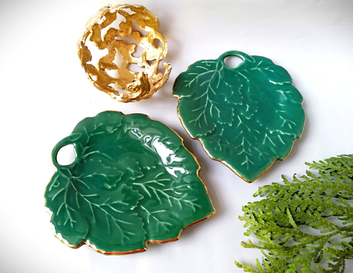 Stylish vintage coaster in the shape of a green vine leaf with gold trim