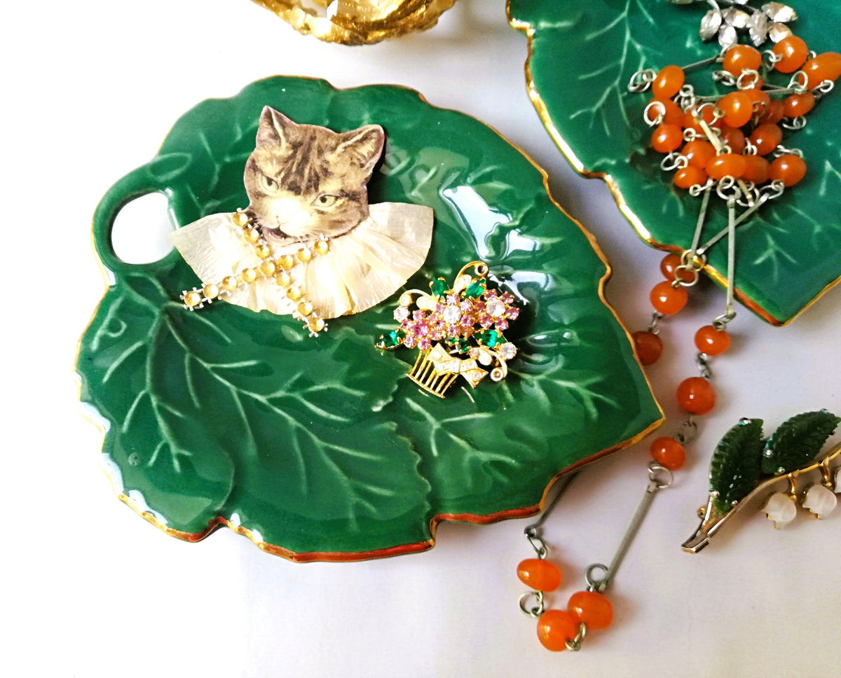 Stylish vintage coaster in the shape of a green vine leaf with gold trim