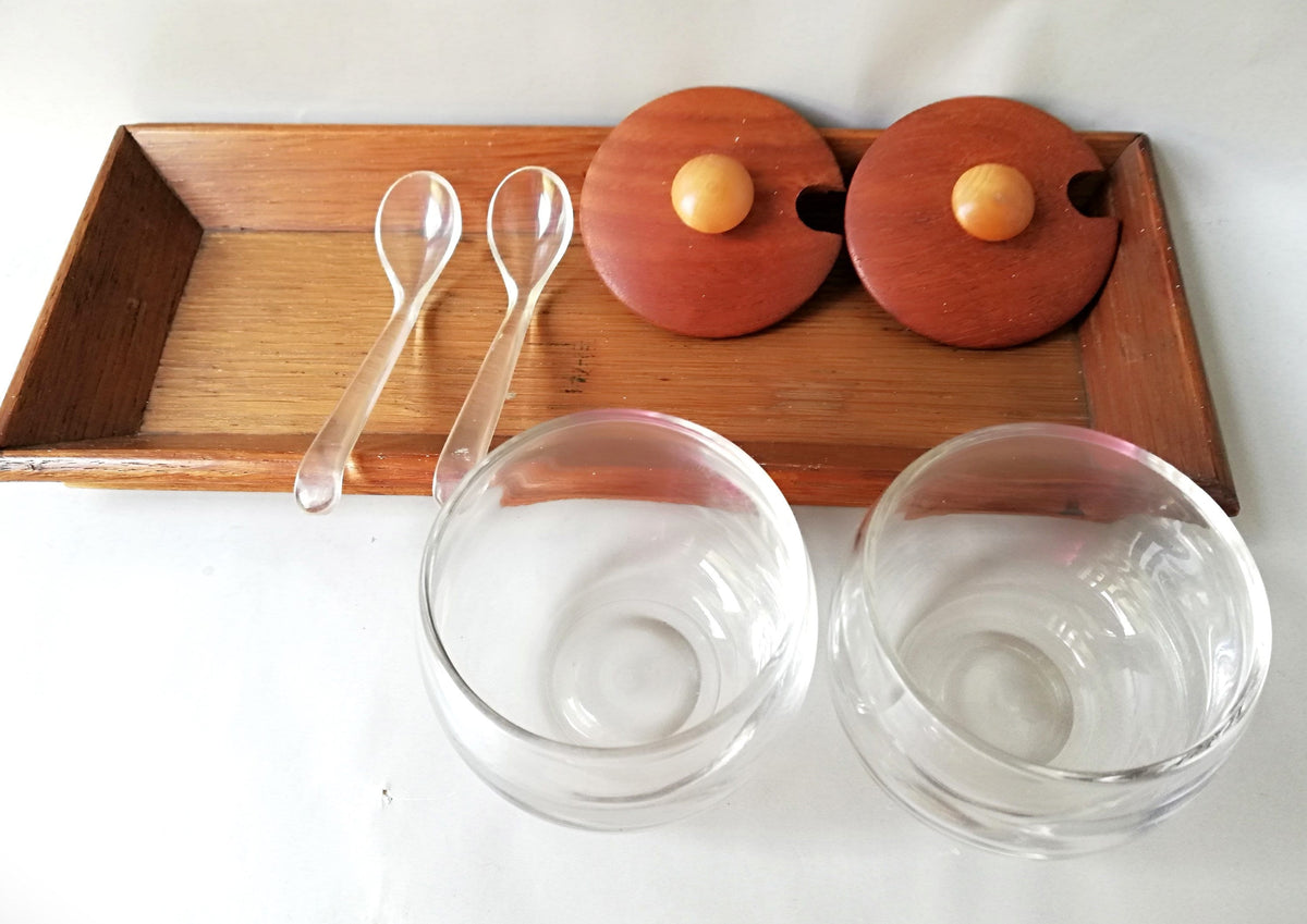 Glass jars with wooden lids and spoons for serving side dishes. Serving dishes for side dishes such as jam, ketchup, horseradish or caviar.