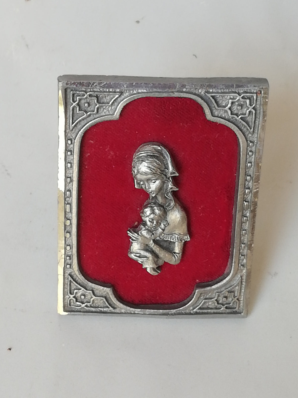 Vintage Madonna and Child on red velvet. Miniature icon with zinc frame and Madonna made of zinc.