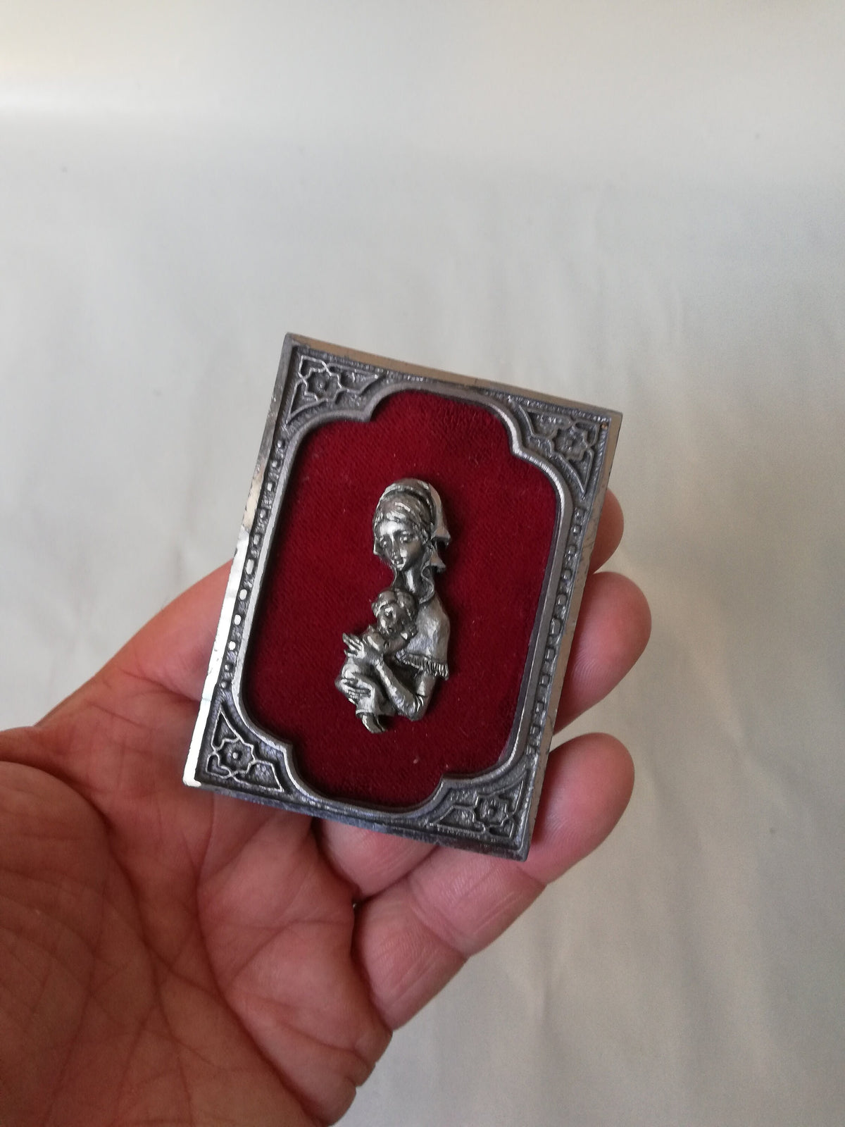 Vintage Madonna and Child on red velvet. Miniature icon with zinc frame and Madonna made of zinc.