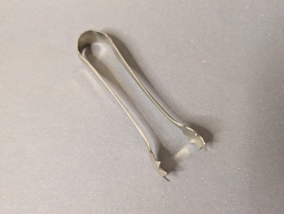 Zuckerzange mit Zuckerwürfeln am Teetisch