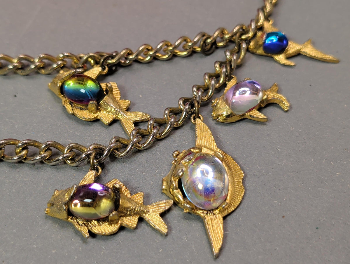 Einzelner goldfarbener Fisch mit blau-grünem Cabochon