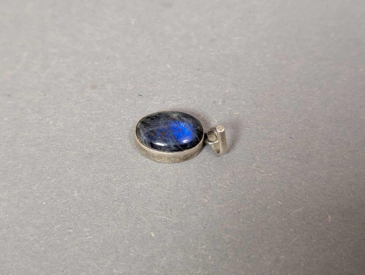 Ovaler dunkler Cabochon mit elektrisch blauem Farbspiel im Licht