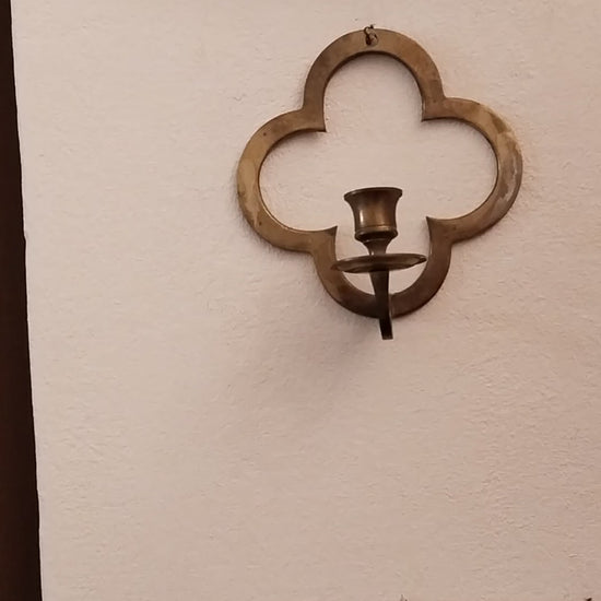 Historischer Wandleuchter aus Messing im Vierpass-Design an einer weißen Wand. video.
