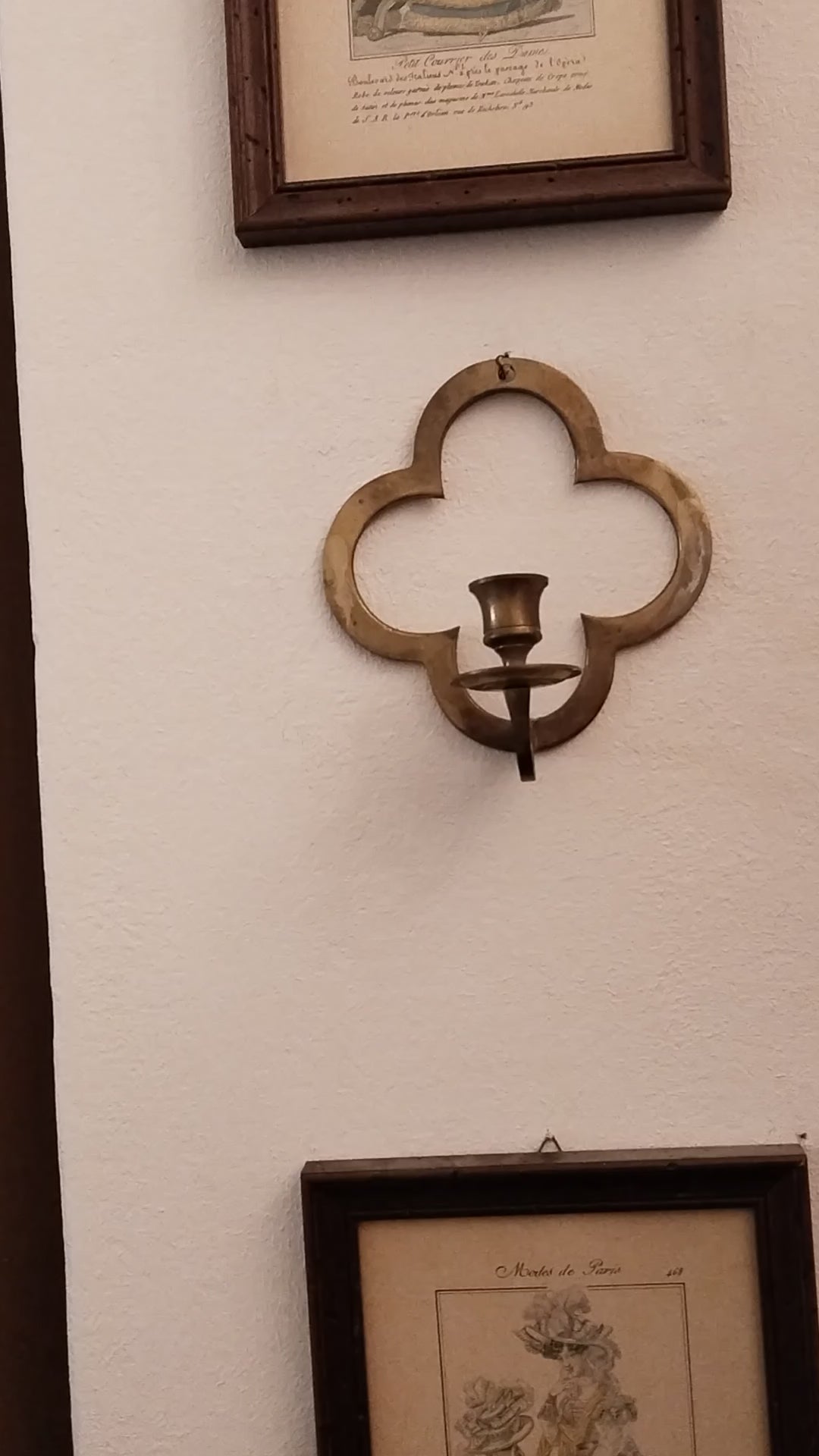 Historischer Wandleuchter aus Messing im Vierpass-Design an einer weißen Wand. video.