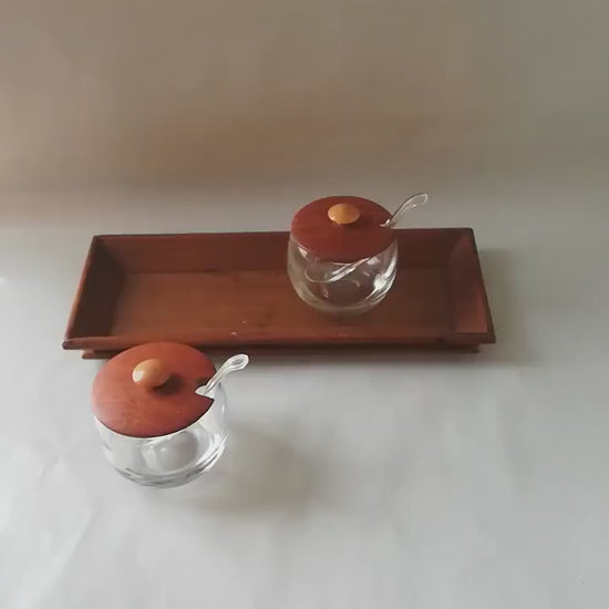 Glass jars with wooden lids and spoons for serving side dishes. Serving dishes for side dishes such as jam, ketchup, horseradish or caviar.