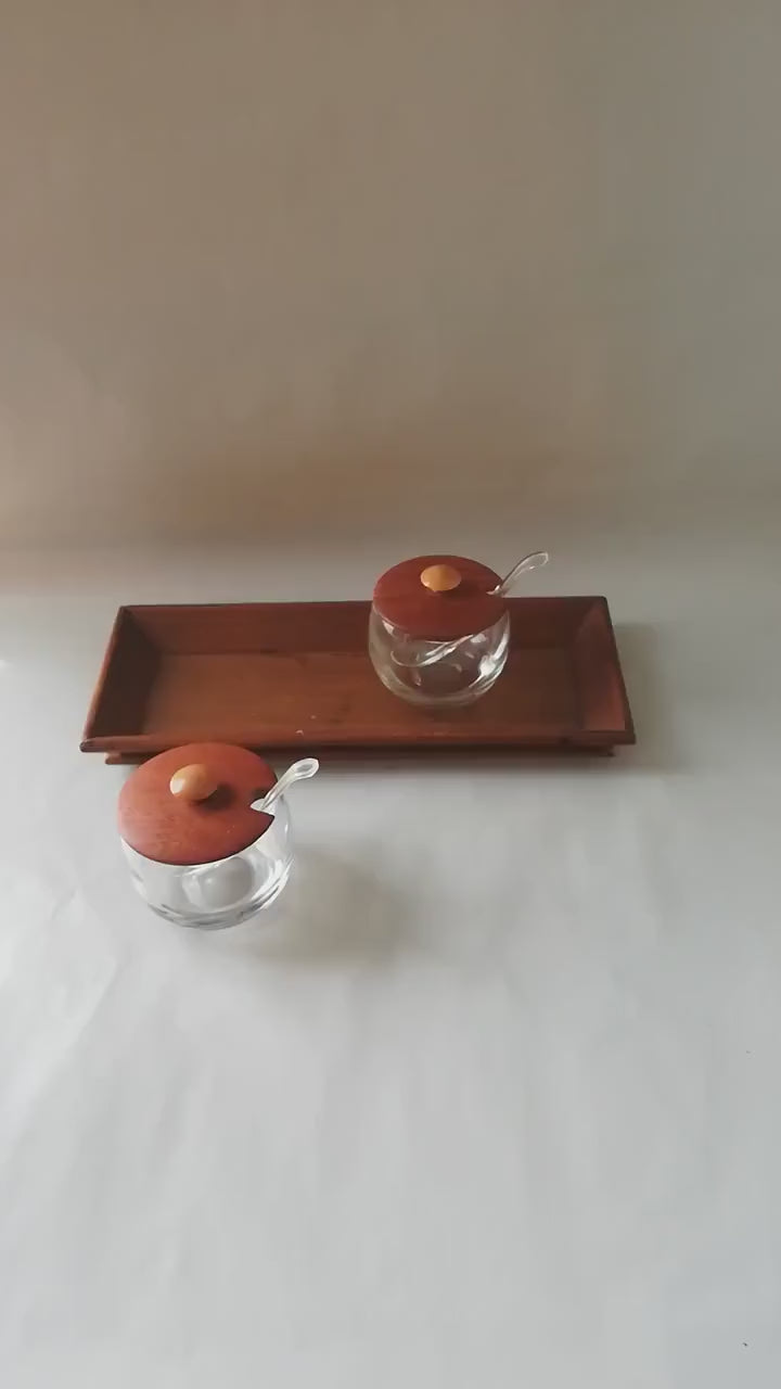 Glass jars with wooden lids and spoons for serving side dishes. Serving dishes for side dishes such as jam, ketchup, horseradish or caviar.